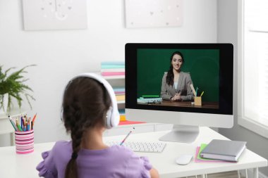 Uzaktan öğrenme, evde çalışma. Covid-19 salgınından dolayı karantina ve tecrit sırasında öğretmenle online okul dersi alan bir kız.