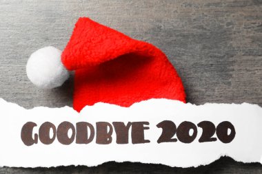 Kağıt sayfa ve metin Elveda 2020 ve gri arka planda Noel Baba şapkası, düz uzanmış
