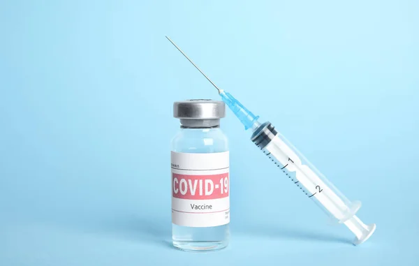 Açık Mavi Zemin Üzerinde Koronavirüs Aşısı Şırınga Olan Şişe — Stok fotoğraf