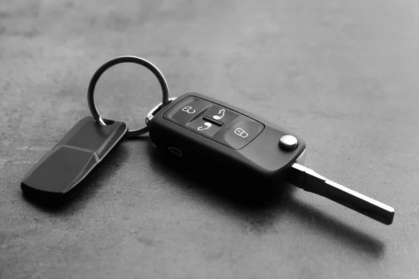 Modern car flip key with trinket on grey background, closeup