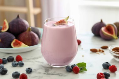 Beyaz mermer masada cam içinde nefis incirli smoothie.