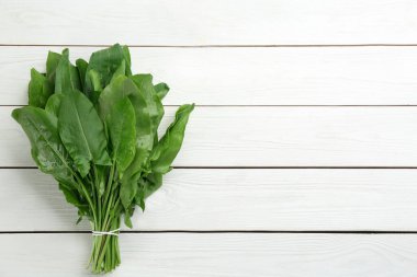 Beyaz ahşap masada taze yeşil kuş yaprakları, üst manzara. Metin için boşluk