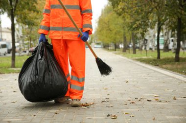 Street cleaner with broom and garbage bag outdoors on autumn day, closeup clipart