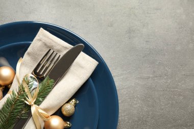 Gri arka planda güzel bulaşık takımları ve Noel dekoru olan şenlik masası, üst manzara. Metin için boşluk