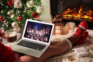 MYKOLAIV, UKRAINE - 23 Aralık 2020: Harry Potter ve Filozof Stone 'un filmini evinde şöminenin yanındaki dizüstü bilgisayarda izleyen tatlı içkili kadın, yakın plan. Sıcak kış tatili atmosferi