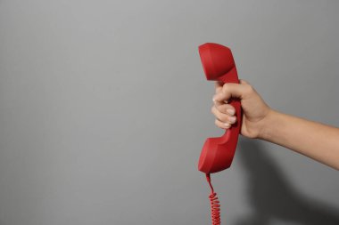 Açık gri arka planda kırmızı kablosuz telefonu olan bir kadının yakın görüntüsü, mesaj için boşluk. Yardım hattı kavramı