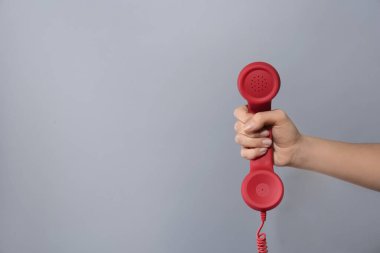 Açık gri arka planda kırmızı kablosuz telefonu olan bir kadının yakın görüntüsü, mesaj için boşluk. Yardım hattı kavramı