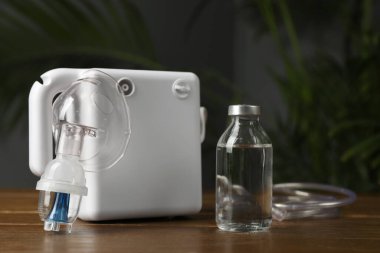 Modern nebulizör, yüz maskesi ve ahşap masa üzerinde sıvı ilaç. Solunum cihazları