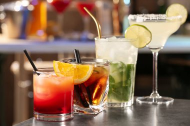 Bardaki gri masada farklı lezzetli kokteyller.