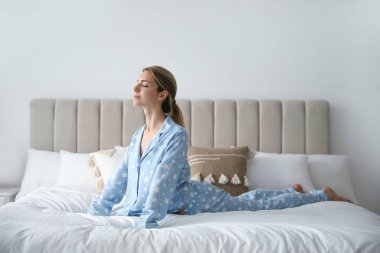 Evde yatakta jimnastik yapan genç bir kadın. Sabah sporu