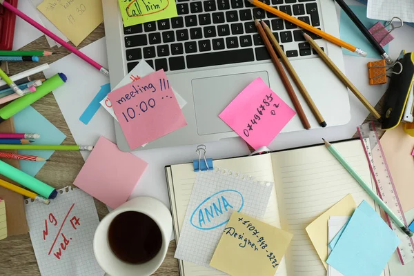 Laptop, notes and office stationery in mess on desk, top view. Overwhelmed with work