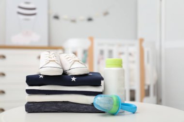 Beyaz masa içinde bebek kıyafetleri, ayakkabılar ve aksesuarlar yığını