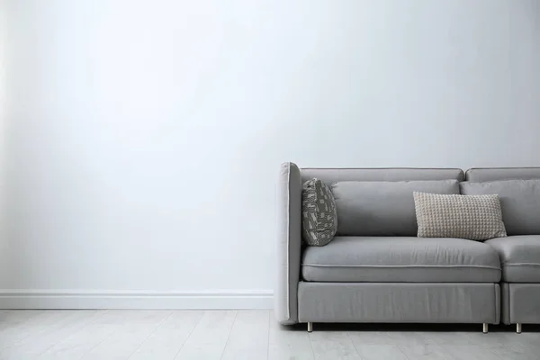 有枕头的灰色沙发靠近白色的墙壁在时尚的客厅内部 案文的篇幅 — 图库照片