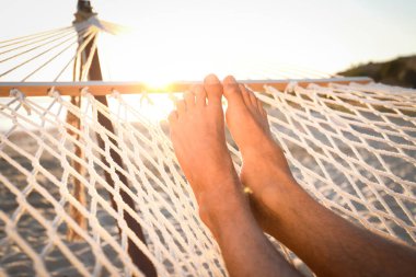 Gün batımında plajda hamakta dinlenen adam, yakın çekim.