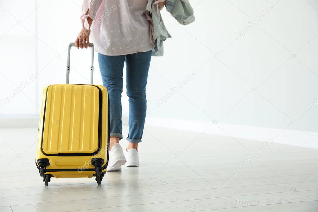 Woman with yellow travel suitcase in airport. Space for text