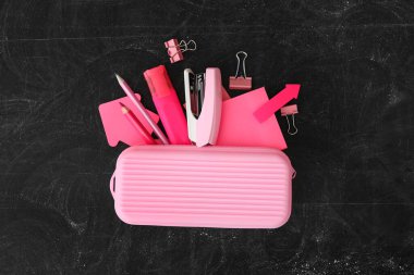 Pembe kalem kutusu ve tahta üzerinde farklı kırtasiye malzemesi. Okula geri dön.