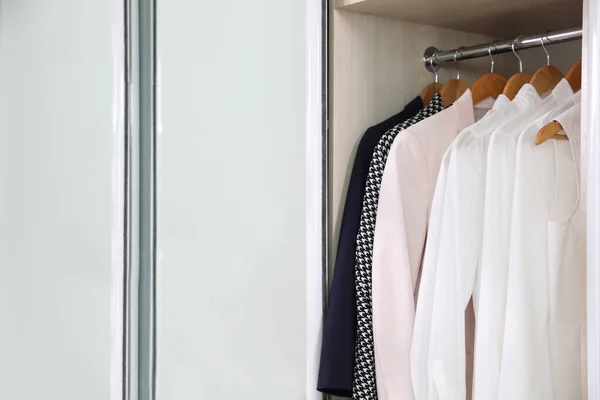 Wardrobe closet with different stylish clothes in room, closeup