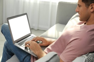 Evdeki koltukta dizüstü bilgisayar kullanan adam, yakın plan.