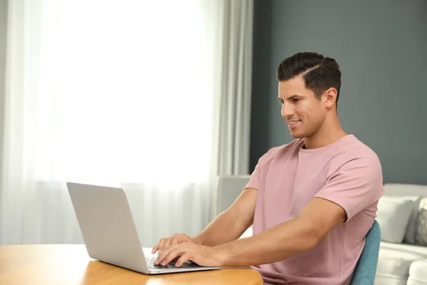 男人用笔记本电脑在客厅的木制桌子上搜寻 — 图库照片
