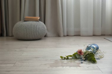 Broken blue glass vase and bouquet on floor in room. Space for text clipart