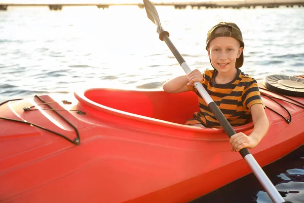 Happy little boy kayaking on river. Summer camp activity