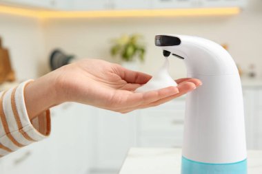 Mutfakta otomatik sabun makinesi kullanan kadın, yakın plan.