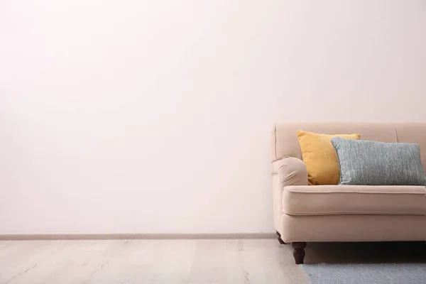 光の壁の近くに快適なベージュのソファ屋内 テキストのためのスペース シンプルな内装 — ストック写真