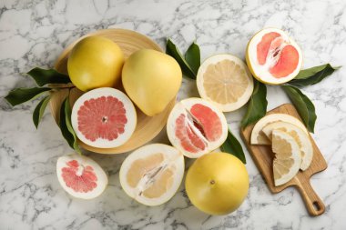 Taze kesim ve beyaz mermer masa üzerinde yaprakları ile tüm pomelo meyveleri, düz yatıyordu