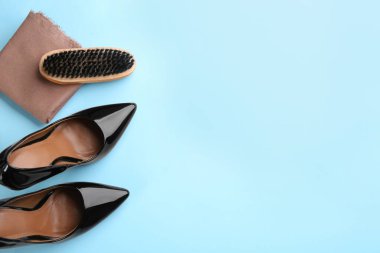 Açık mavi arka planda ayakkabı bakım aksesuarları ve ayakkabıları olan düz bir kompozisyon. Metin için boşluk