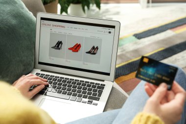 Kredi kartı olan bir kadın evde online alışveriş için dizüstü bilgisayar kullanıyor.