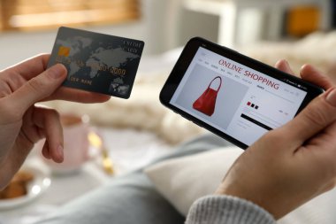 Kredi kartı olan bir kadın evde online alışveriş yapmak için akıllı telefon kullanıyor.