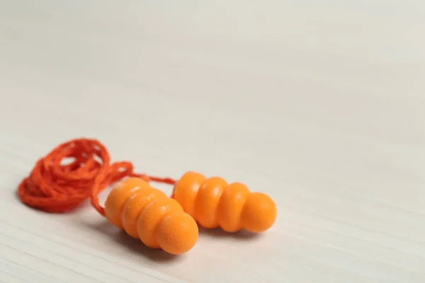 Pair of ear plugs on white wooden background, closeup. Space for text