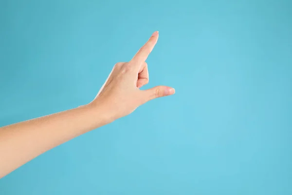 女人指着浅蓝色背景的东西 手指的手势 — 图库照片