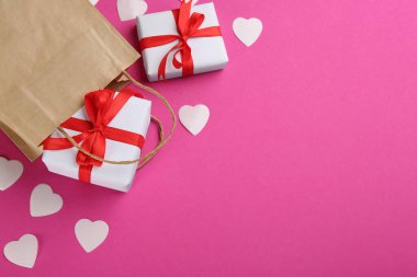 Güzel hediye kutuları, kese kâğıdı ve pembe arka planda kalpler, mesaj için yeri olan düz bir yer. Sevgililer Günü kutlaması