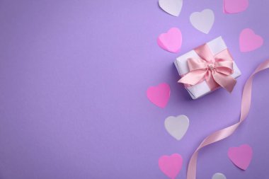 Hediye kutusu, kurdele ve menekşe arka planda kalpler, metin için yeri olan düz bir yer. Sevgililer Günü kutlaması