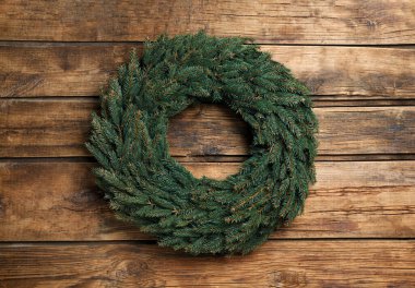 Tahta arka planda köknar dallarından yapılmış Noel çelengi.