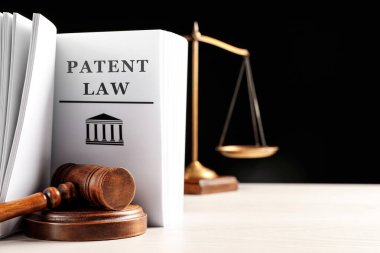 Hakimin tokmağı, patent hukuku kitabı ve siyah arka planda beyaz masanın üzerindeki teraziler. Metin için boşluk