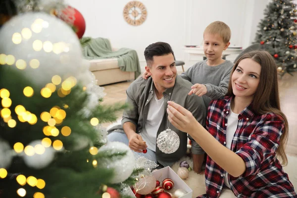 かわいい子供がいる幸せな家族一緒に家でクリスマスツリーを飾る — ストック写真