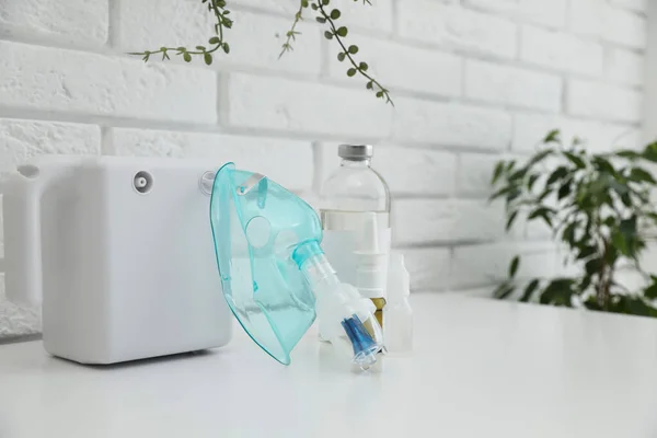 レンガの壁の近くの白いテーブルの上に顔のマスクや薬と現代のNebulizer 吸入用設備 — ストック写真