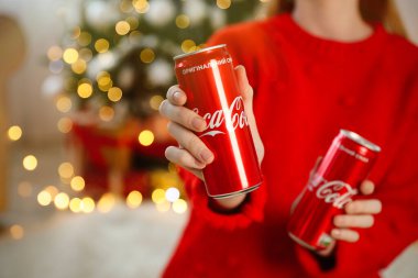 MYKOLAIV, UKRAINE - 01 Ocak 2021: Coca-Cola kutularıyla bulanık Noel ağacına karşı gelen kadın, yakın plan