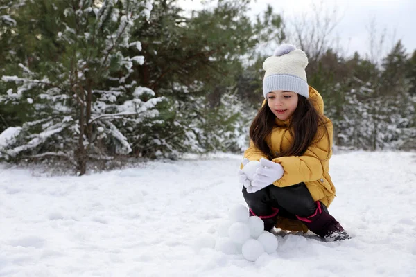 可爱的小女孩在冬天的森林里打滚雪球 — 图库照片