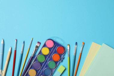 Açık mavi arkaplanda farklı kırtasiye malzemesi, metin için boş alanı olan düz bir yer. Okula geri dön.