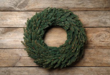 Tahta arka planda köknar dallarından yapılmış Noel çelengi.