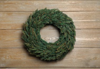 Tahta arka planda köknar dallarından yapılmış Noel çelengi.