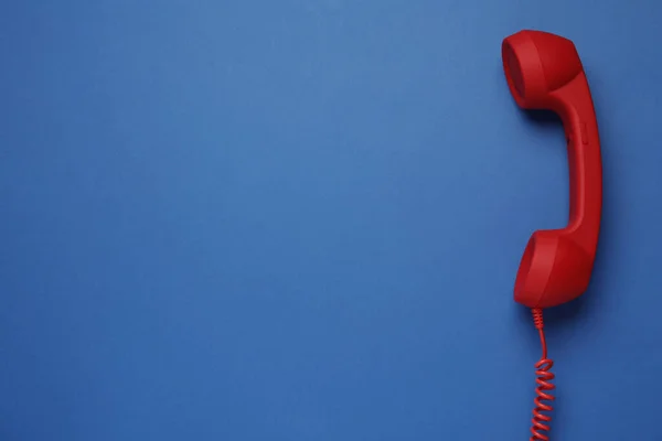 蓝色背景的红色带绳电话听筒 顶视图 热线电话的概念 — 图库照片