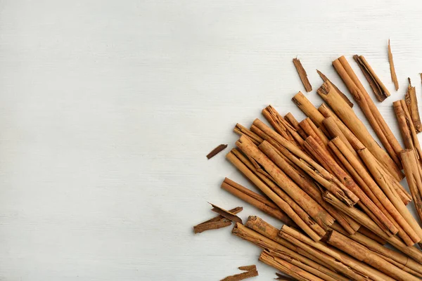 stock image Aromatic cinnamon sticks on white wooden table, flat lay. Space for text