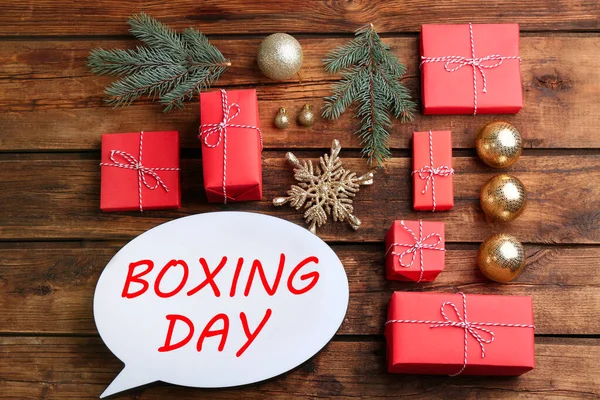 stock image Speech bubble with phrase BOXING DAY and Christmas decorations on wooden background, flat lay