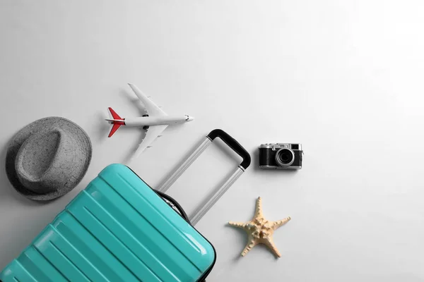 Flat lay composition with suitcase and travel accessories on grey background. Summer vacation