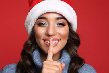 Kırmızı arka planda Noel Baba şapkalı güzel bir kadın. Noel partisi