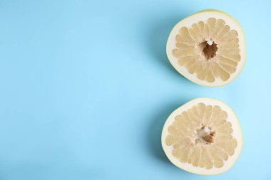 Açık mavi arka planda taze kesilmiş pomelo meyvesi, düz. Metin için boşluk